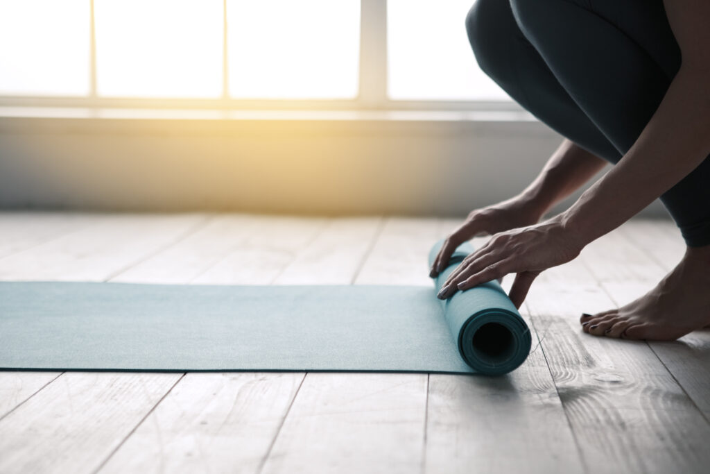 Pair of hands unfolding a yoga mat