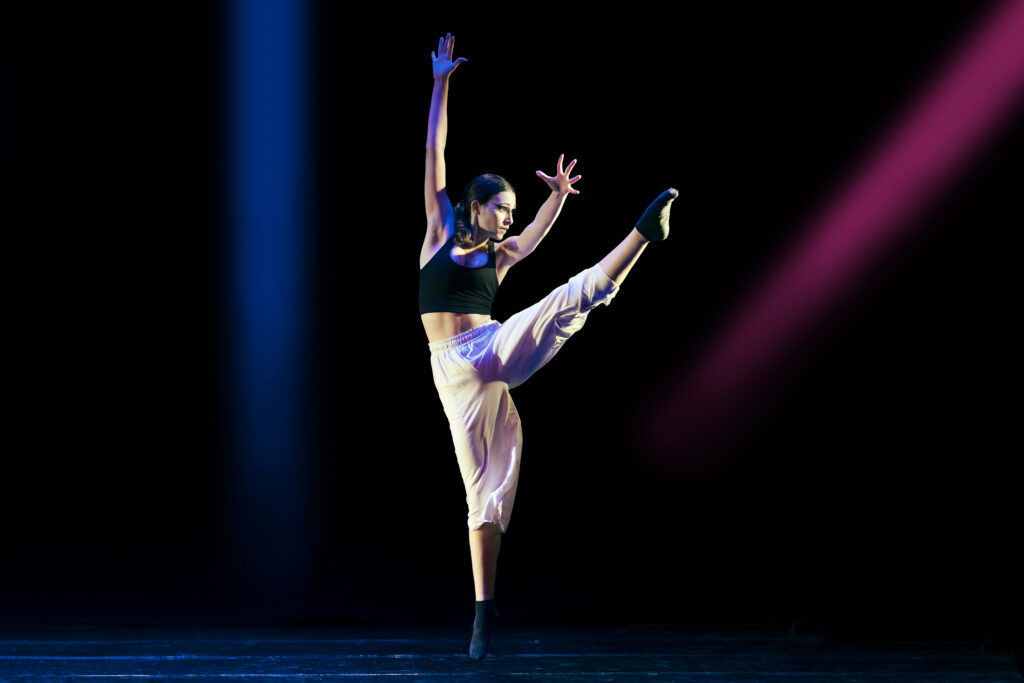 Teenage girl dancing contemporary dance on stage with colorful lights
