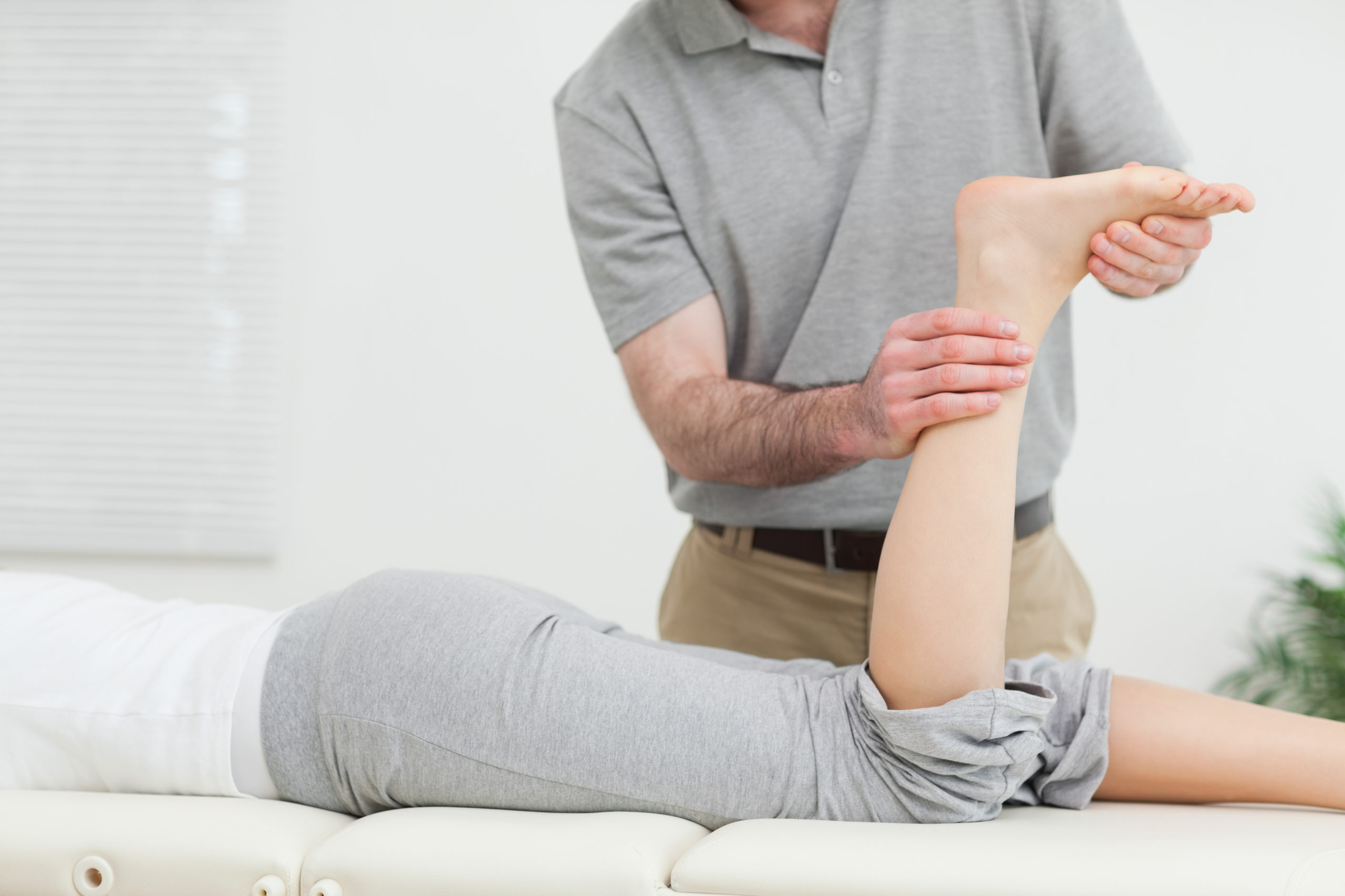 Woman lying forward while a physiotherapist examines her ankle