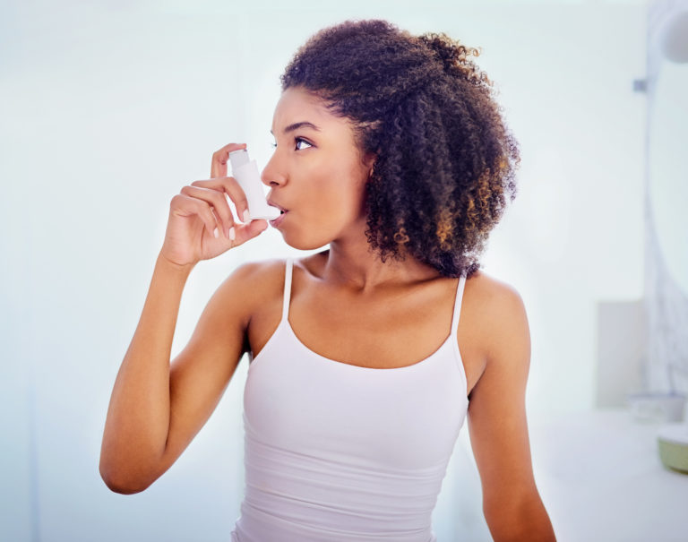 Young Black woman using an inhaler