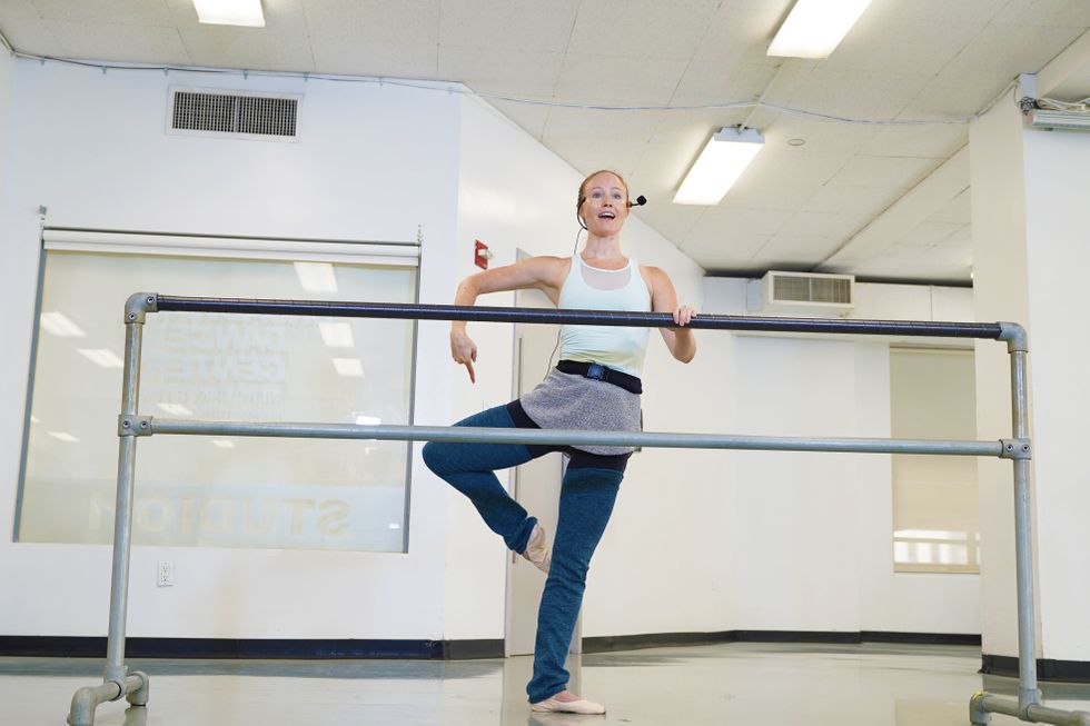 Deanna Doyle stands behind a barre and demonstrates passe