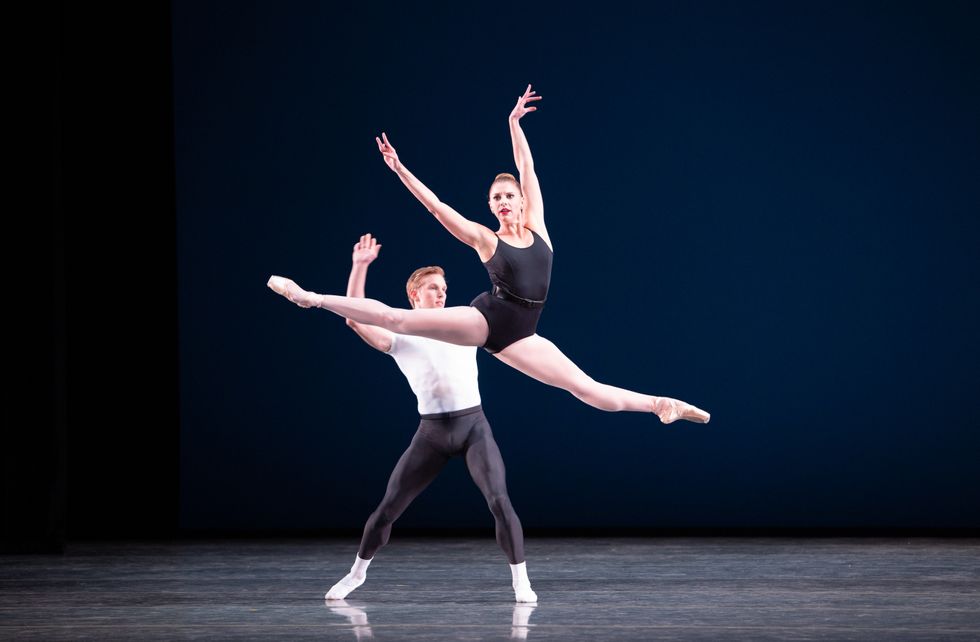 Chase Swatosh, in lack tights and a white T-shirt, tosses Lauren Fadeley into a grand sissone. She wears a black leotard, pink tights and pointe shoes.