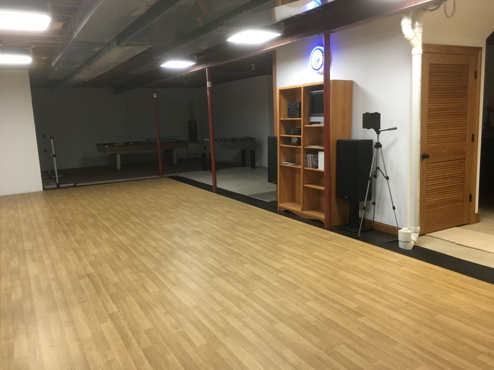 A large basement room outfitted with sprung wood floors and a sound system.