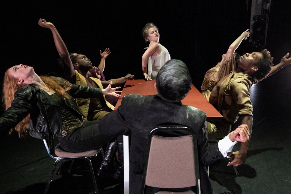 UA Little Rock dance students onstage sit around a table, each striking a different pose.