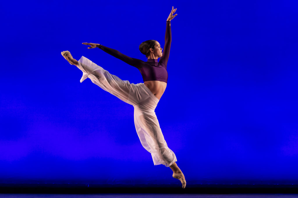 A dancer midair in an energetic sauté