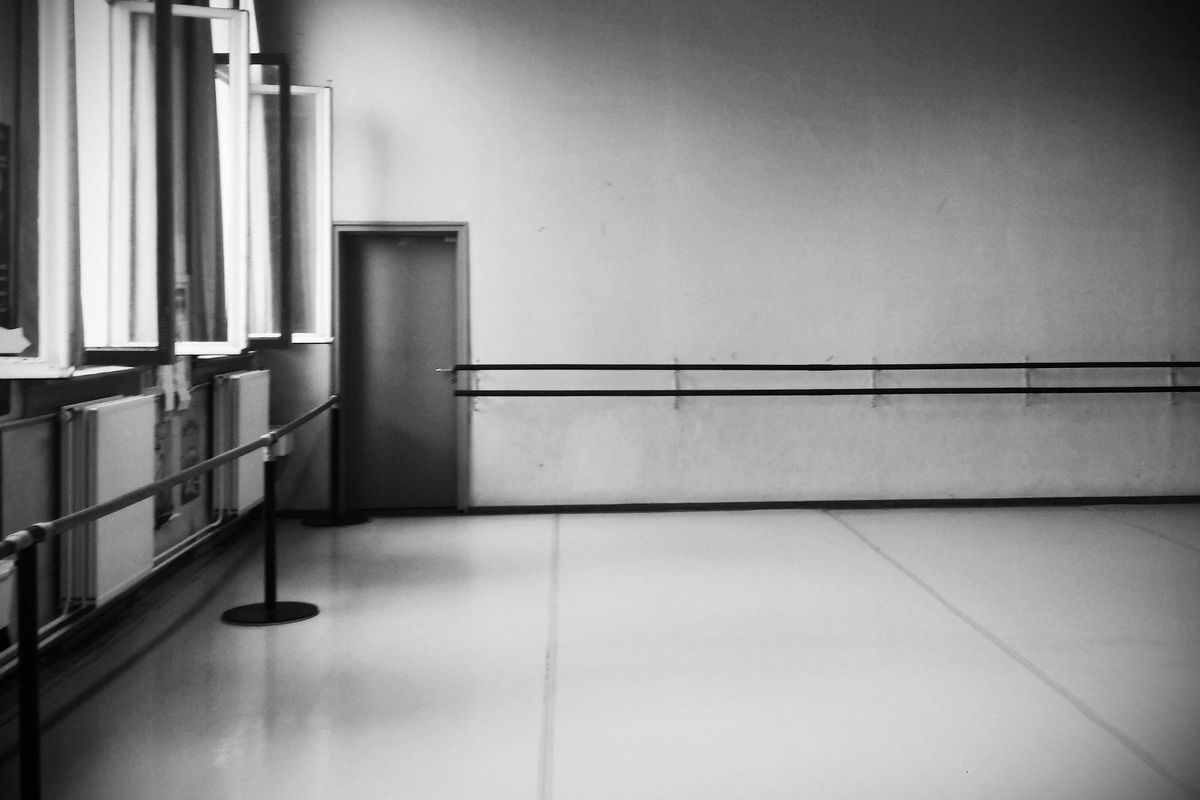 Black and white photo of an empty ballet studio, seen from the front corner of the studio.