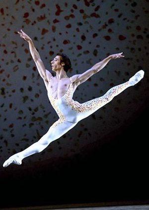 Christophe Maraval leaps in the air, wearing a white spotted unitard. 
