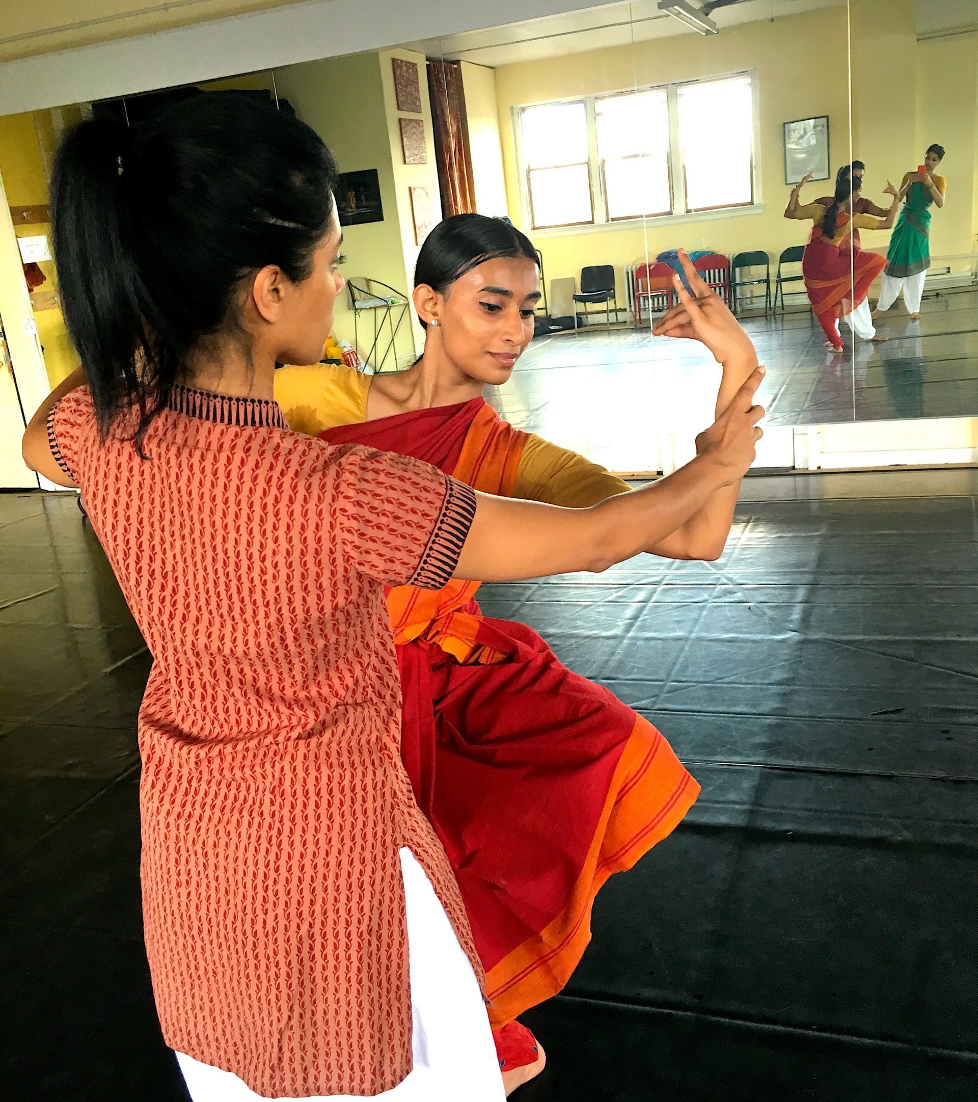 Ramaswamy corrects a students arm placement, adjusting her wrist.