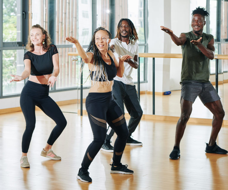 Excited happy group of young dancers training in studio in front of mirror