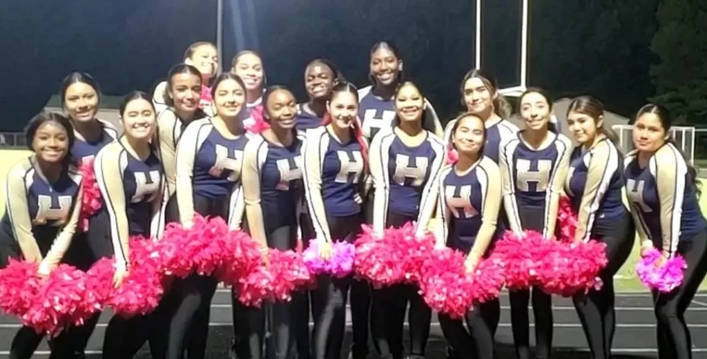 Members of The Hylton Dance Team smiling at the camera and holding pink pom poms