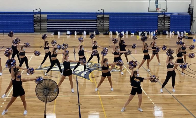 The University of New Haven Dance Team practice a routine with pom poms in a school basketball court