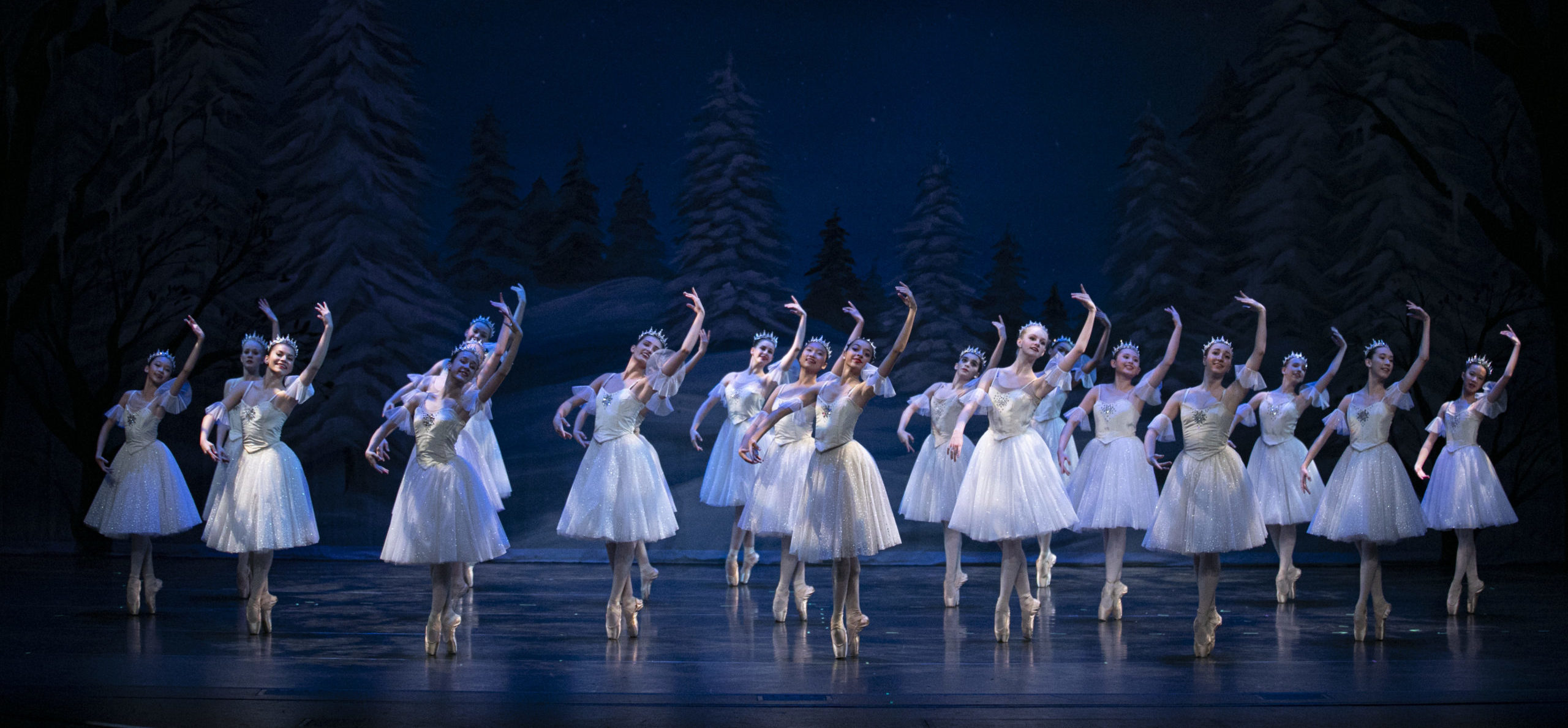 A group of ballerinas on stage all dressed in white