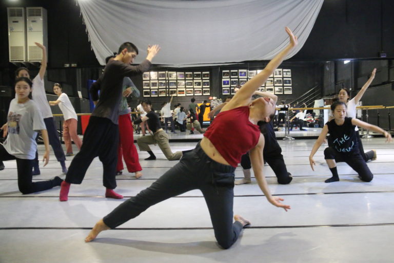 A still of a group of dancers in a studio in movement
