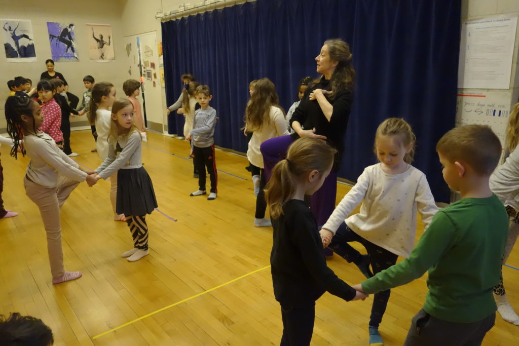 A dance teacher instructing a group of young children
