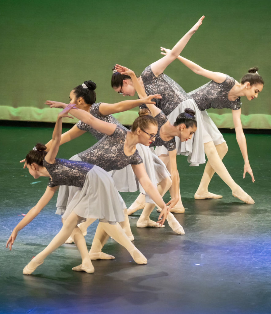 Group of dancers in a line holding a ballet position