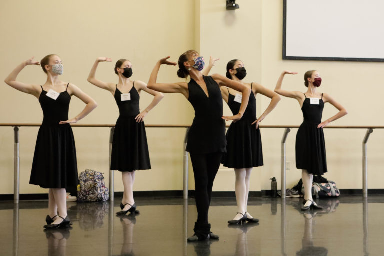 Image of masked dance educator Carmela Gallace teaching character dance to a class of students