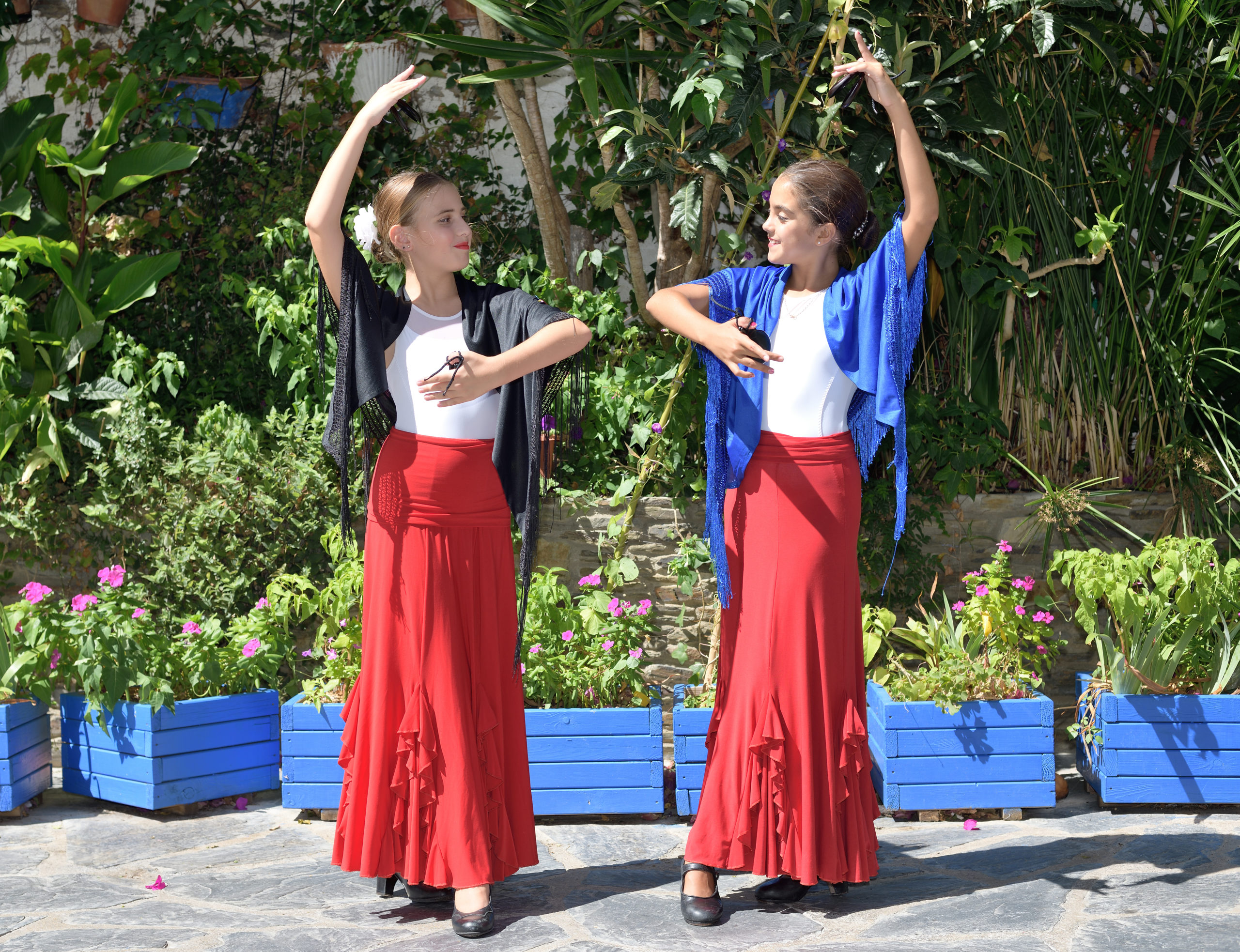 Two girls are dancing flamenco. They are in a symmetrical position with the typical handkerchief