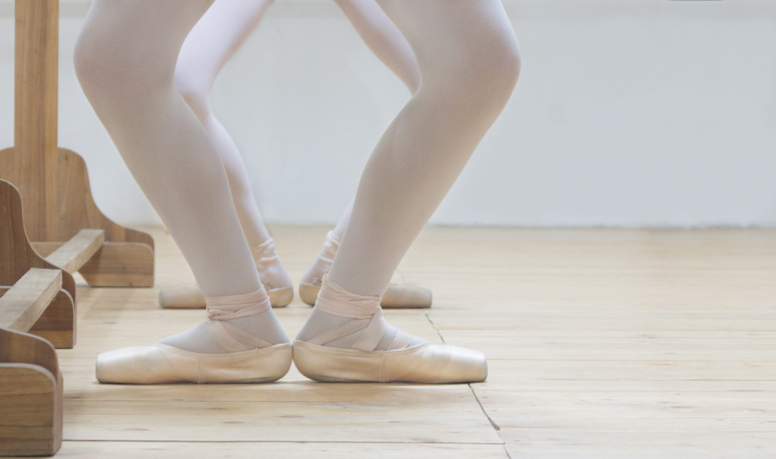 Ballet dancers feet at demi-plie positions at the barre
