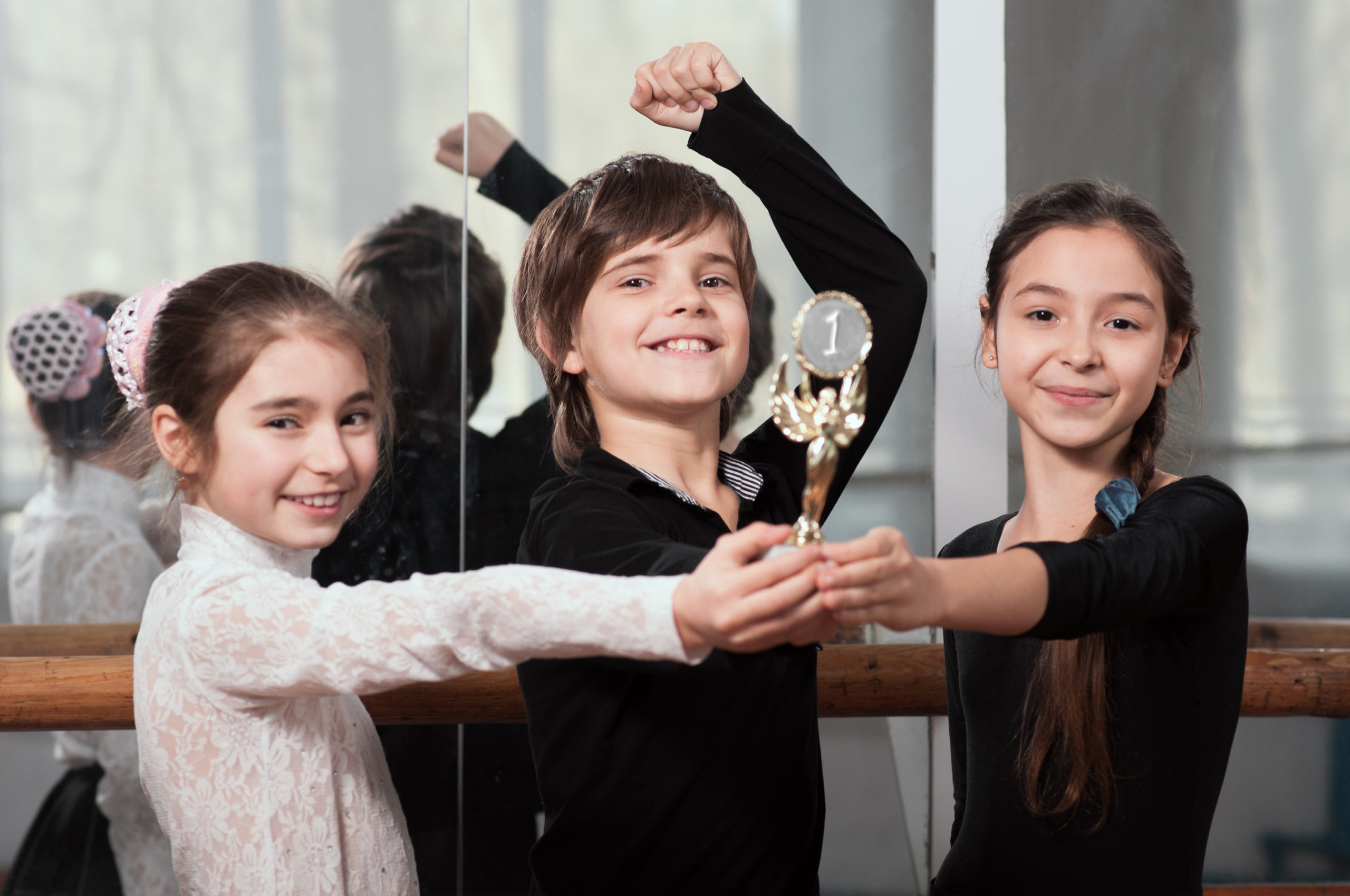 Three young dancers holding a trophy