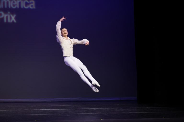 Image of male dancer dressed in white jumping on stage