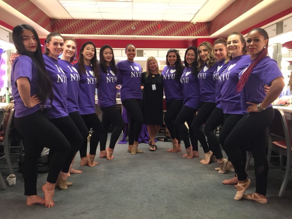 Group of NYU students with educator Deborah Damast holding a pose while standing in a semi-circle