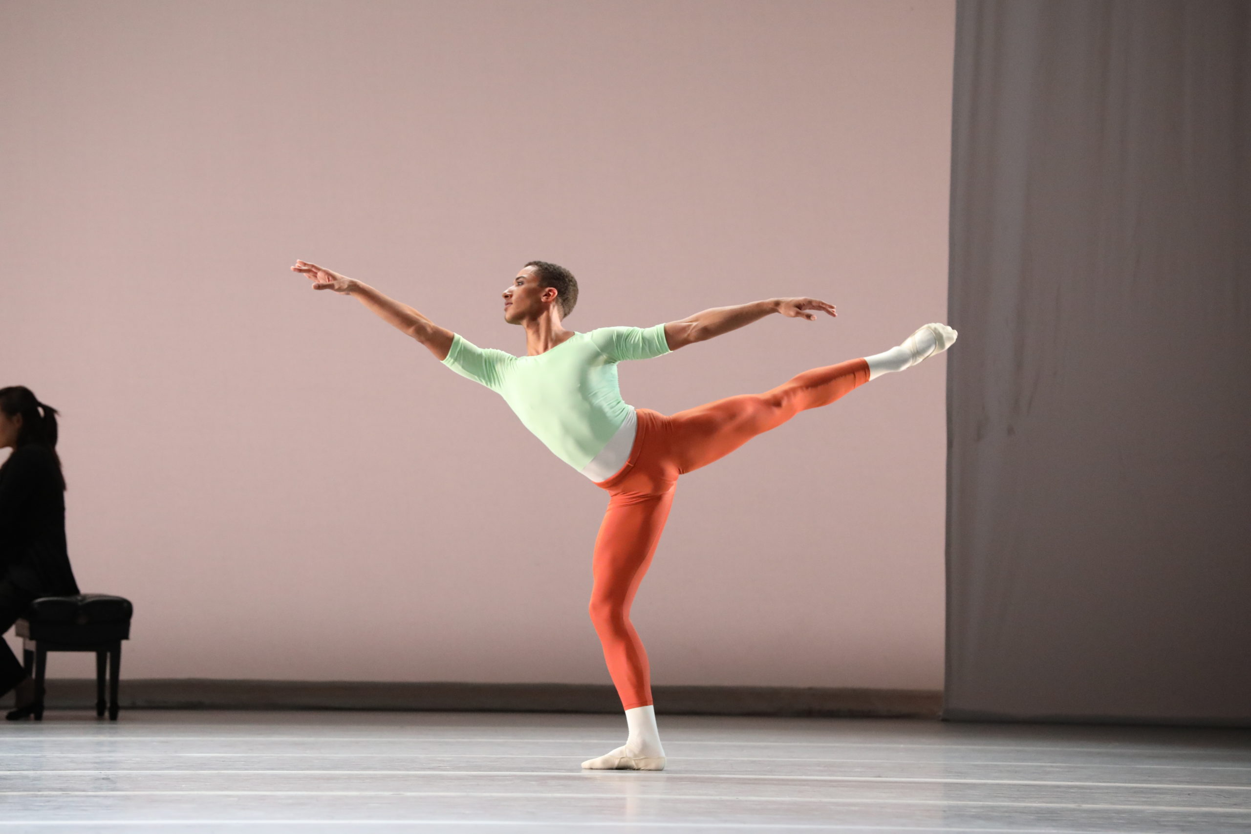 Image of dancer on stage wearing a pastel green top and orange tights