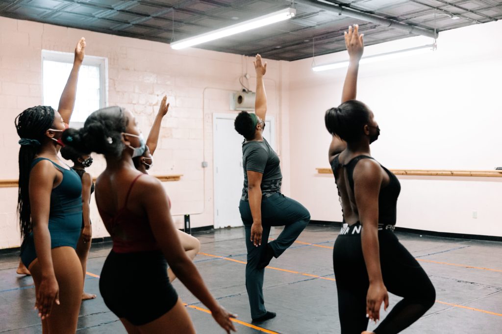A student teacher teaches students a dance move in a studio classroom.