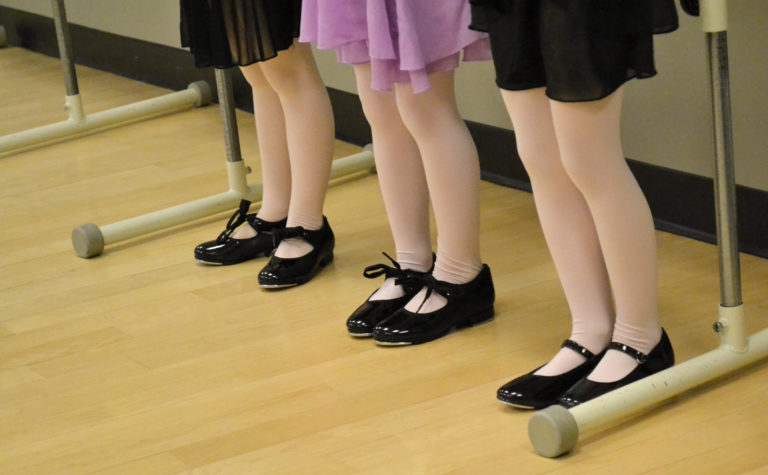 Three dancers feet wearing tap shoes