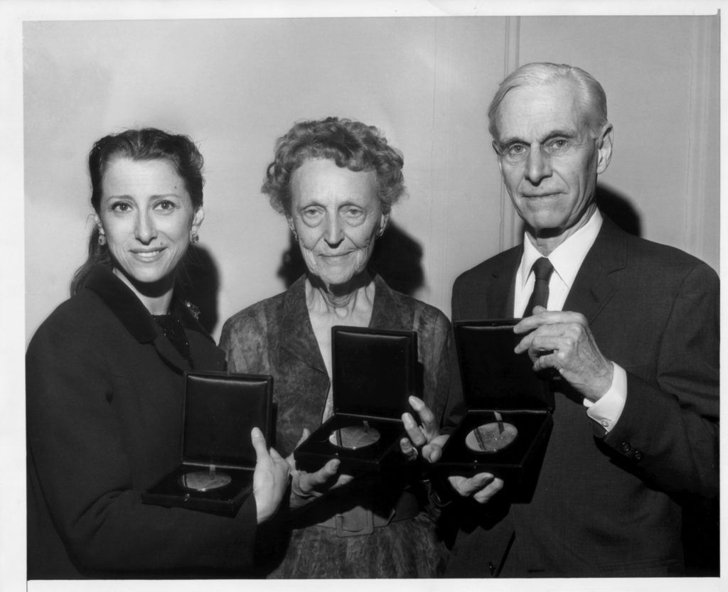 Three people post holding awards.