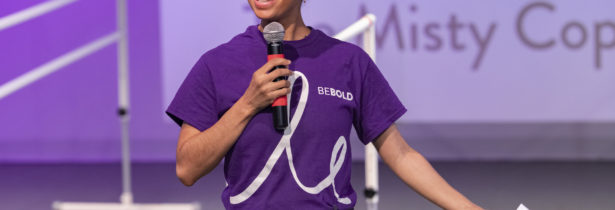 Misty Copeland wearing a purple tshirt and holding a mic