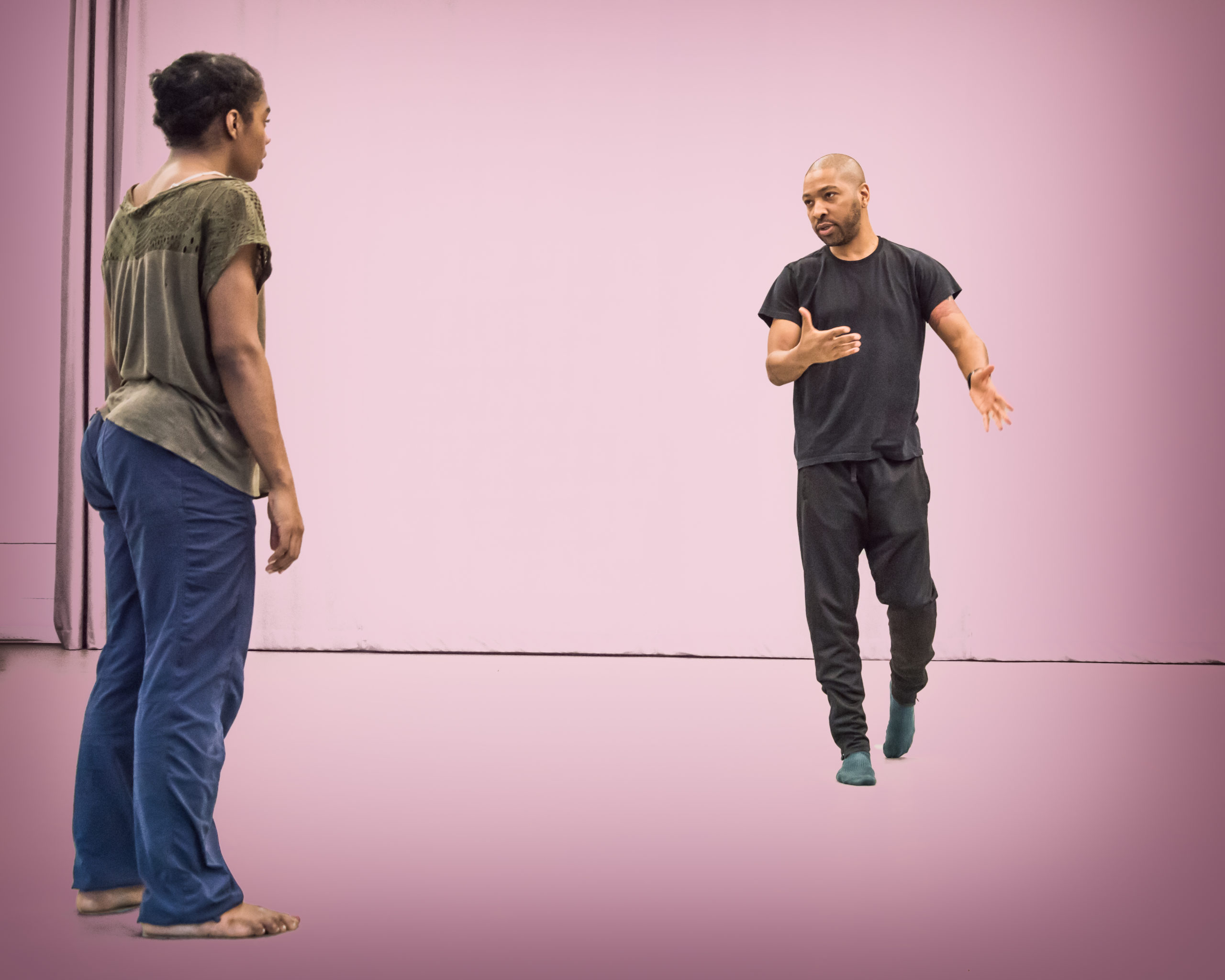 Kyle Abraham rehearses with Kayla Farrish. The photo has a pink background
