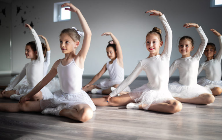 Group of happy children exercising ballet in studio together
