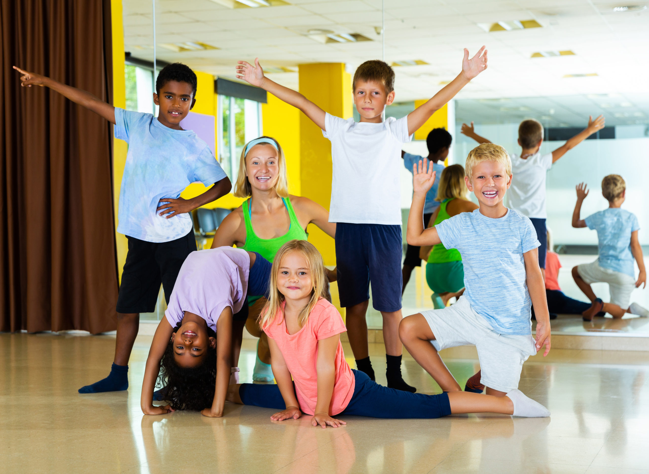 Group portrait of happy dance students with dance teacher in center in a studio.