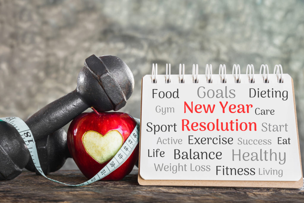 new year goals with red apple, dumbbell and resolution list on paper