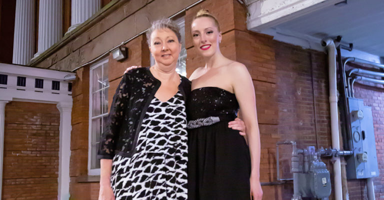 Dance studio owners, a mother and daughter, posing in front of a building.