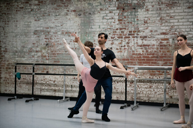 Photo of dance educator Davit Karapetyan assisting a student with an arabesque.