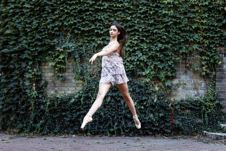Ballet dancer jumping with green ivy wall on backgound