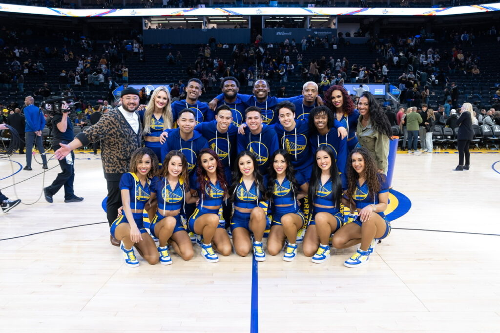 The Golden State Warriors dance team poses for a group photo on the court.