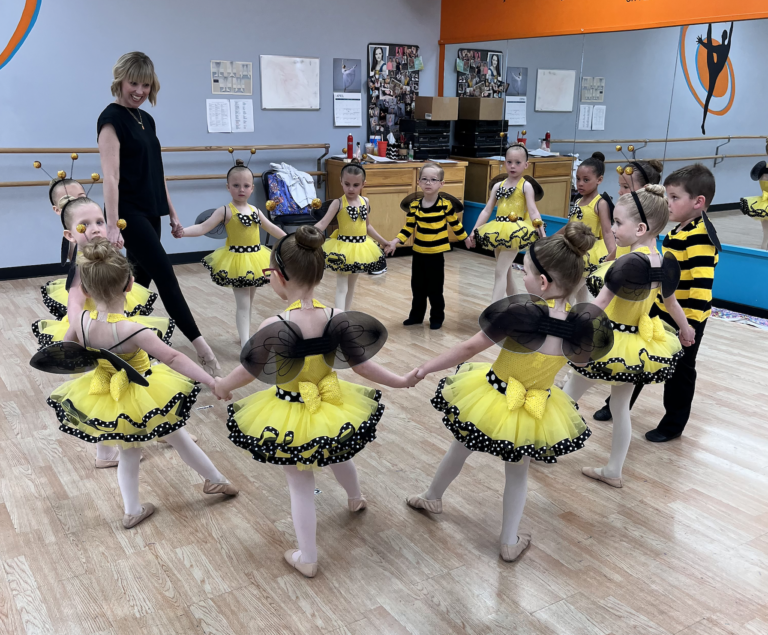 Kellie Satterly stands in a circle of preschool students wearing bumblebee costumes.