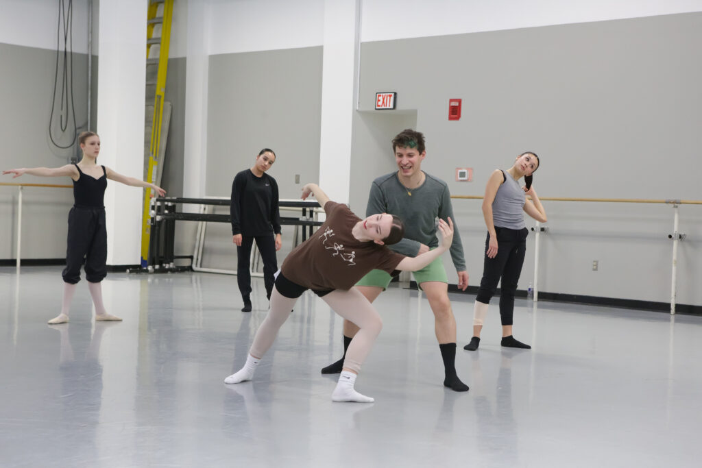 Barry Kerollis smiles while guiding a teenage ballet student through a contemporary position.