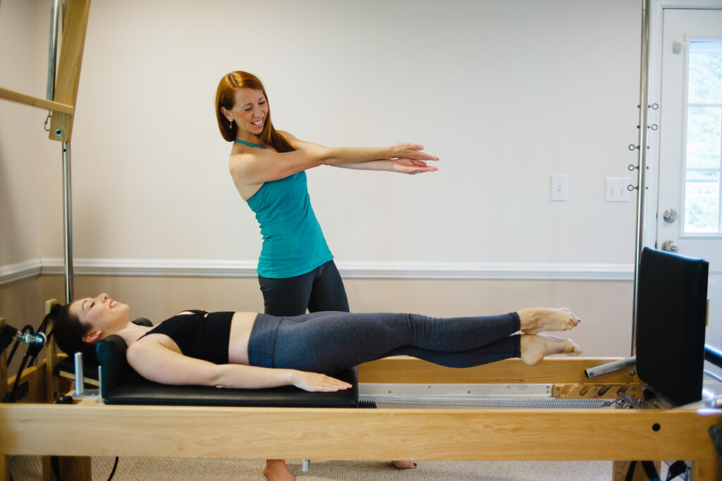 Kerry Shea demonstrating to a dancer lying on a Pilates reformer.