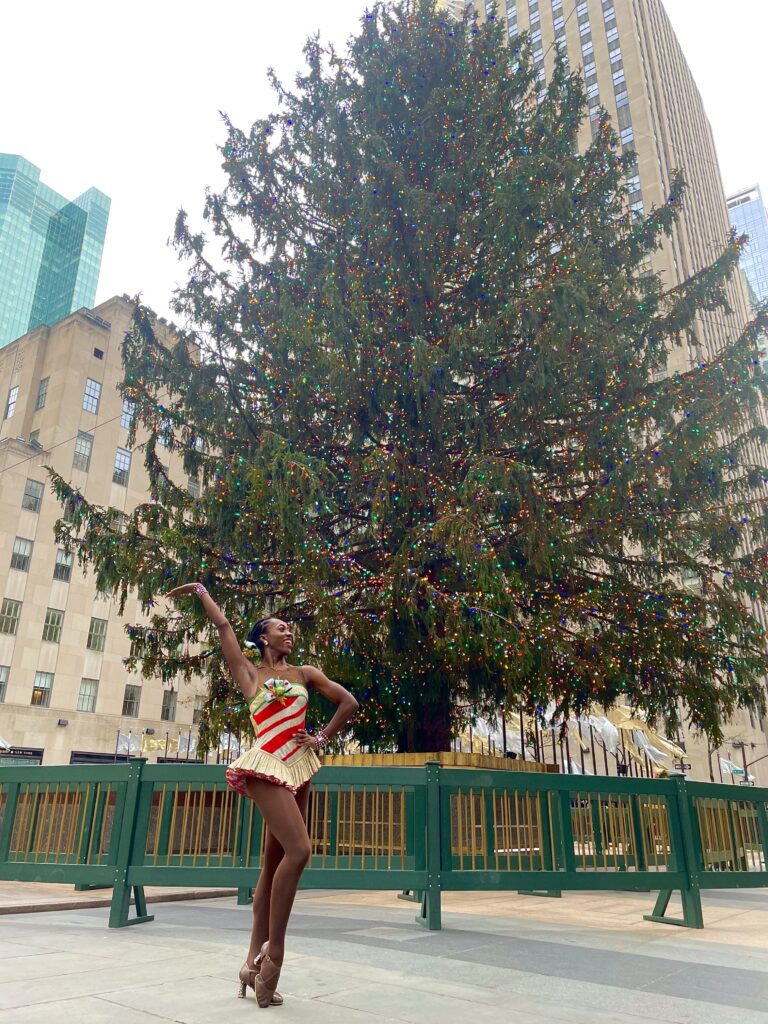 Alexis Payton poses in front of the Radio City Music Hall Christmas tree.