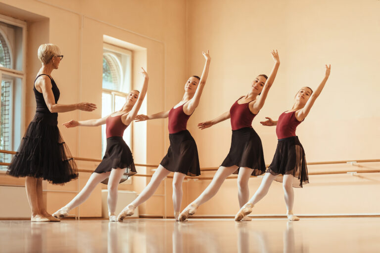 Small group of ballerinas practicing with their teacher at ballet studio.