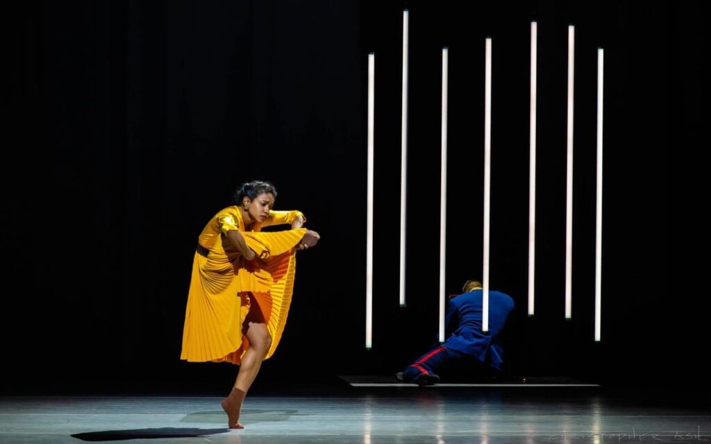 Dandara Veiga performing in a yellow costume on stage.
