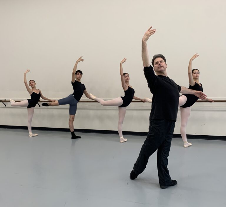 Dance educator Ethan Brown wearing all-black dance attire teaching student at the barre
