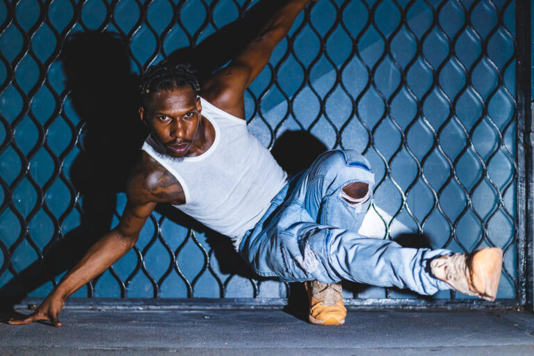Dancer Omari Wiles in blue jeans and white tshirt holding a dance pose.