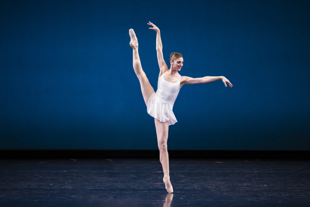Ballet West Principal Artist Emily Adams wearing a white costume on stage in CONCERTO BAROCCO.