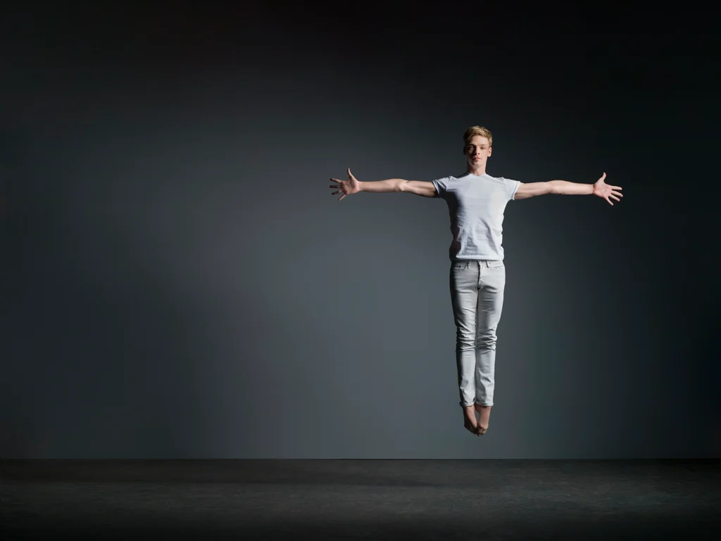 James Hobley in a leap against grey background.