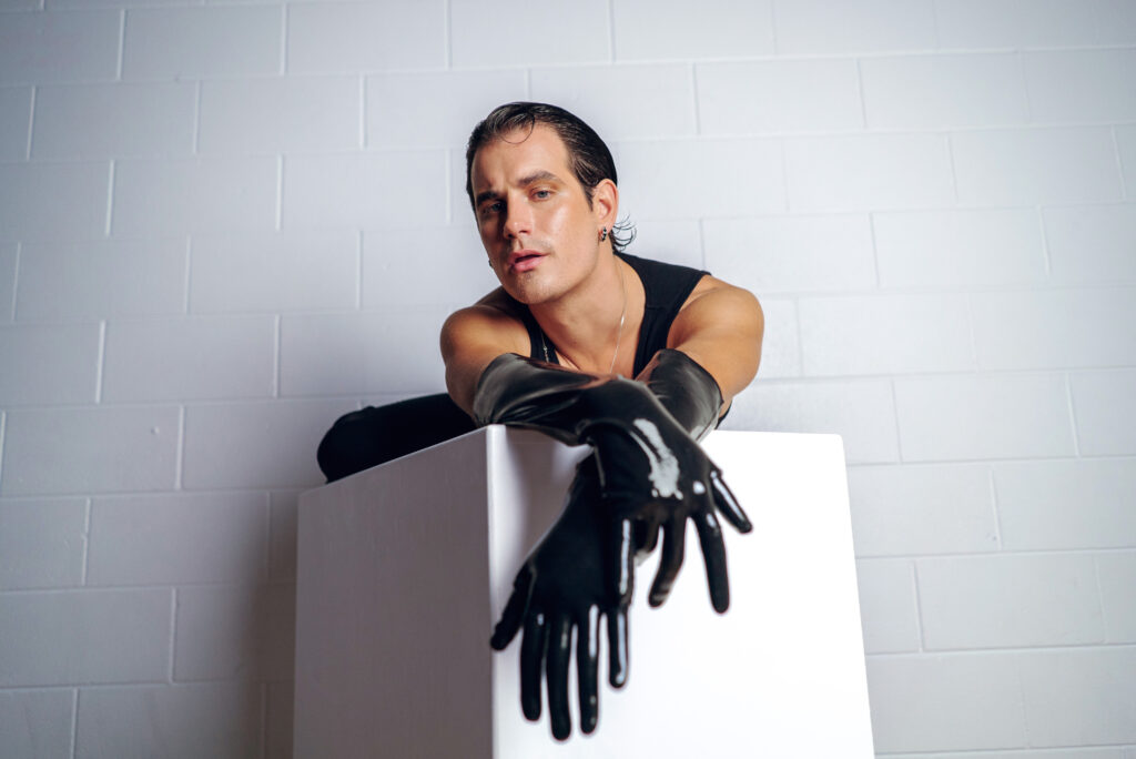 Kiel Tutin posing in a white background wearing black gloves.