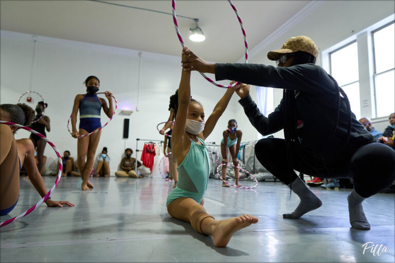 Chanel Holland teaching a young dancer in a studio.